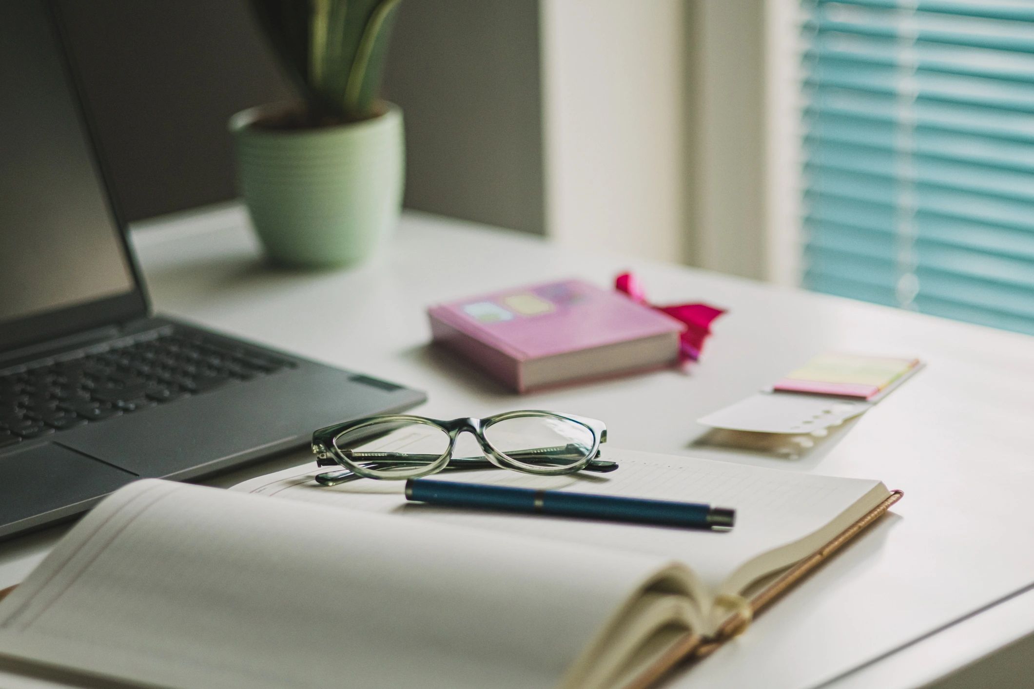 Office desk with laptop, coffee, glasses, and office supplies